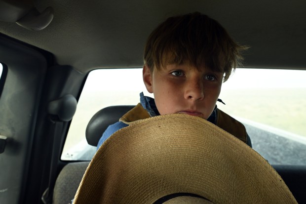 Woods Leach, 10, holds onto his large cowboy hat as his father David drives the family out for an early season branding at Chico Basin Ranch on May 10, 2024. (Photo by Helen H. Richardson/The Denver Post)