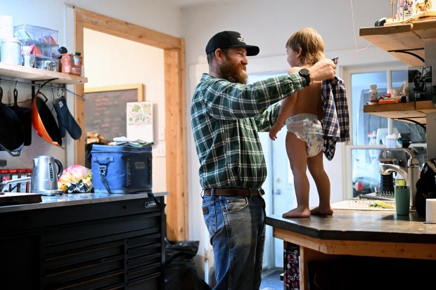 Duke Phillips IV, left, dresses his son Duke V, 3, in a similarly matched plaid shirt to start the day early in the morning at Chico Basin Ranch on Feb. 2, 2024. (Photo by Helen H. Richardson/The Denver Post)