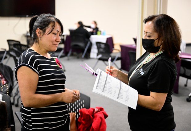 Vuela for Health community health worker Magda Ortiz, right, writes down information for patient Angeles Sanchez, left, during a heart health screening event at Vuela for Health on Feb. 25, 2023. (Photo by Andy Cross/The Denver Post)