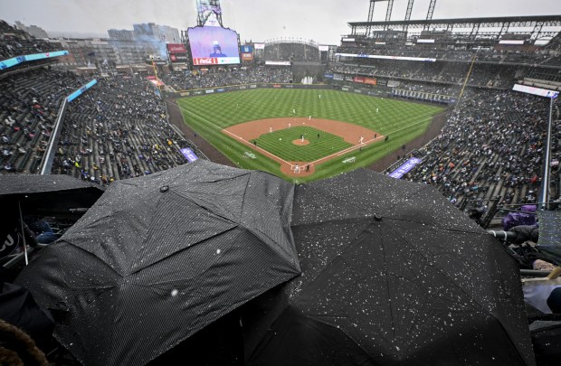 Scott Schwartz and Chris Munson huddle beneath umbrellas during the home opener between the Colorado Rockies and the Athletics at Coors Field in Denver, on Friday, April 4, 2025. (Photo by AAron Ontiveroz/The Denver Post)
