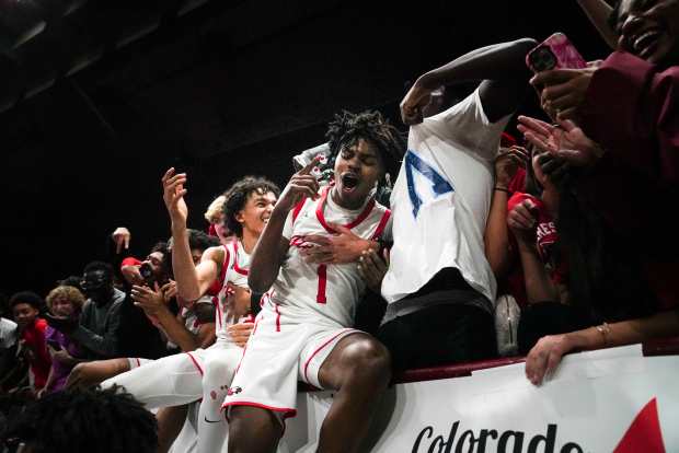 Eaglecrest's Anthony Nettles (1) jumps into the stands with fans after winning the Class 6A Boy's Basketball State Championship game at Denver Coliseum, Saturday, March 15, 2025, in Denver. Eaglecrest High School's Boy's Basketball team won 65-63. (Rebecca Slezak/Special to The Denver Post).