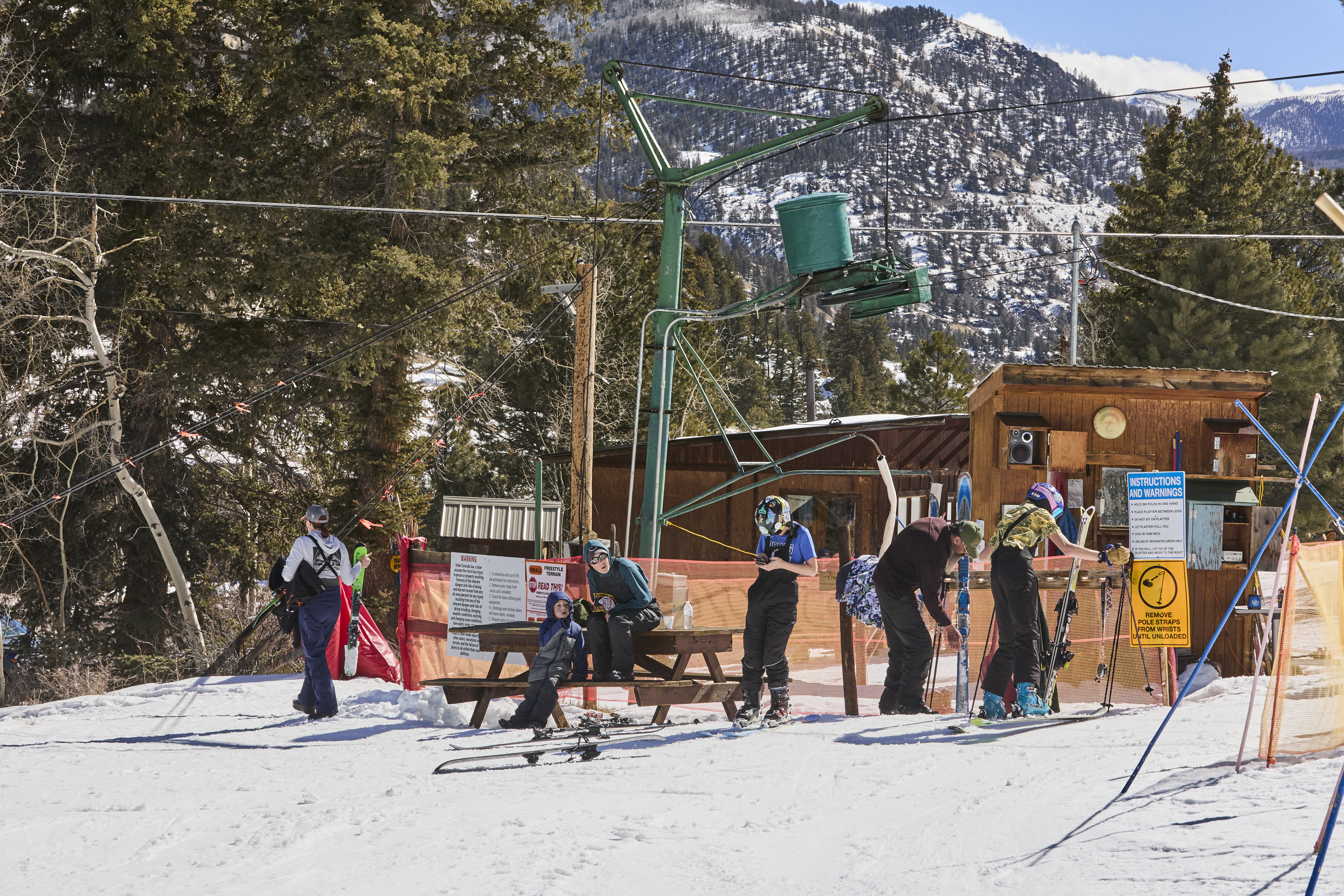 Skiers rest next to the Poma platter lift at the base of the Lake City Ski Hill on Feb. 24, 2025. The lift serves seven runs and terrain park with 274 vertical feet. (Photo by Jacob Spetzler/Special to The Denver Post)