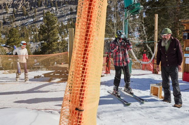 Donal Junak, right, loads Henry Shephard onto the Poma platter rope tow ski lift at the Lake City Ski Hill on Feb. 24, 2025. The Poma platter lift is more challenging to use than a more modern chairlift and often represents a challenge to new skiers. Don Junak is the only full time employee of the hill. (Photo by Jacob Spetzler/Special to The Denver Post)
